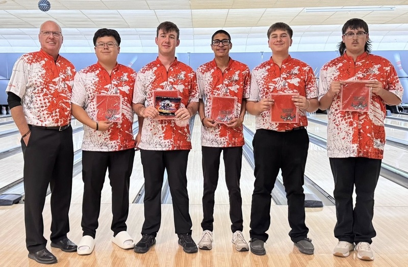 Five male bowlers in orange and white bowling shirts stand with their male coach. All hold certificates and one holds a plaque.