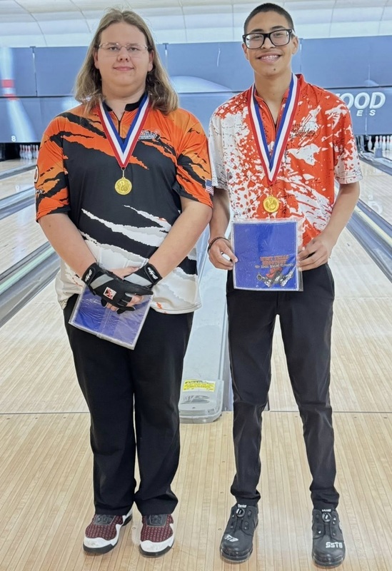 Two male bowlers, one in an orange, black and white bowling shirt and one in an orange and white shirt, wear medals and hold certificates.