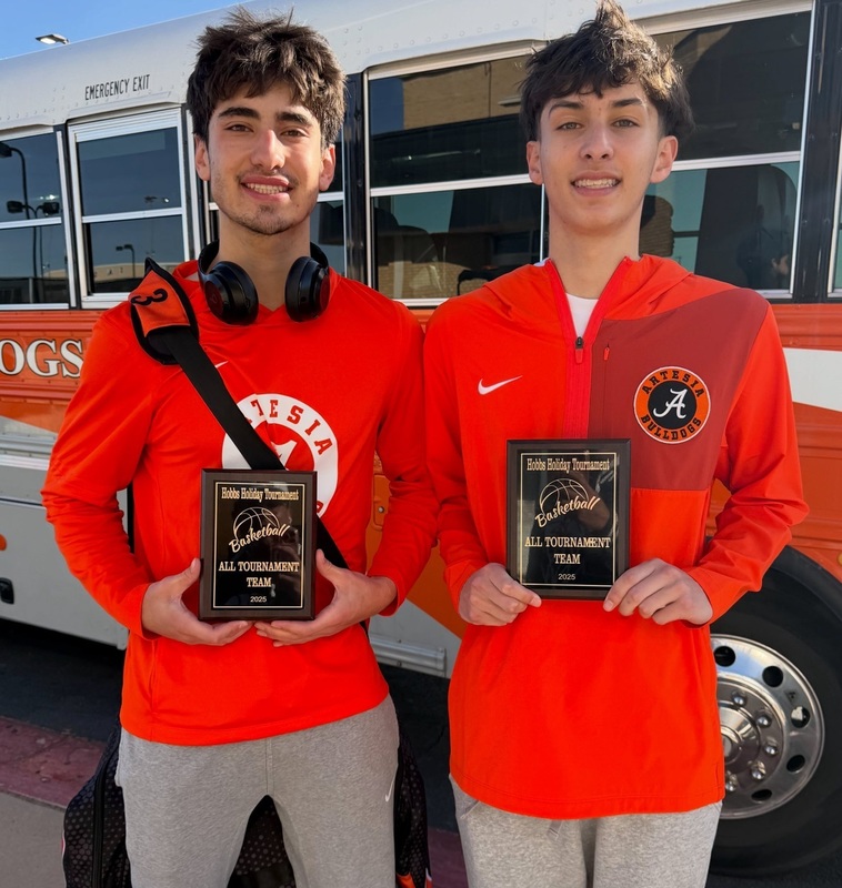 Two teen boys in orange shirts hold All-Tournament Team plaques.