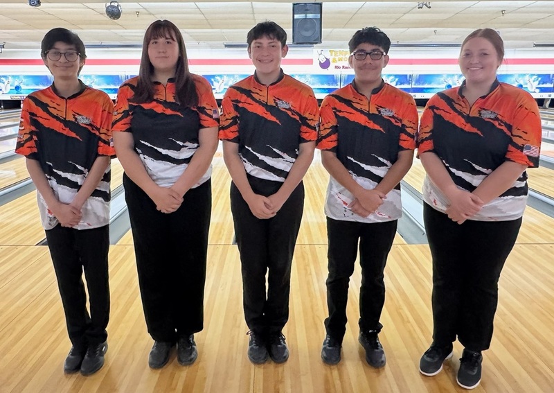 Three male and two female teens in orange, black and white bowling shirts pose for a photo.