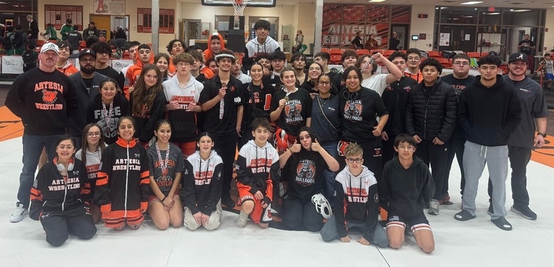 A large group of male and female teens poses for a photo with a male coach.