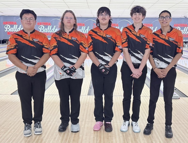 Five male teens in orange, black and white bowling shirts pose for a photo.