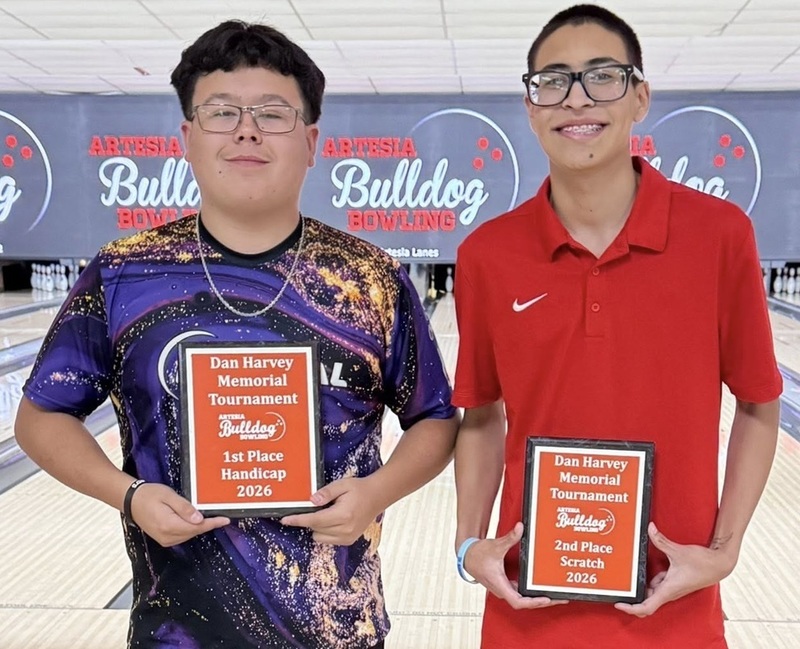 Two male teens smile for a photo holding orange plaques.