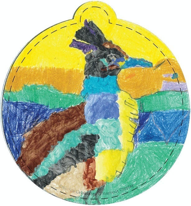 A Christmas ornament colored by a child depicts a roadrunner in browns and blues in front of a yellow and orange sunset.