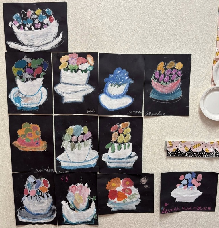 Multiple children's drawings hanging on a wall depict arrangements of flowers.