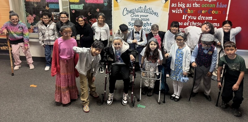 A group of young boys and girls poses for a photo. The children are dressed as elderly people.