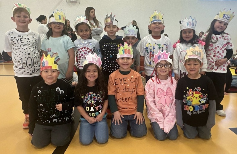 A group of children pose for the camera wearing shirts decorated with multiples of small items.