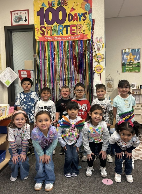 A group of children pose for the camera wearing shirts decorated with multiples of small items.
