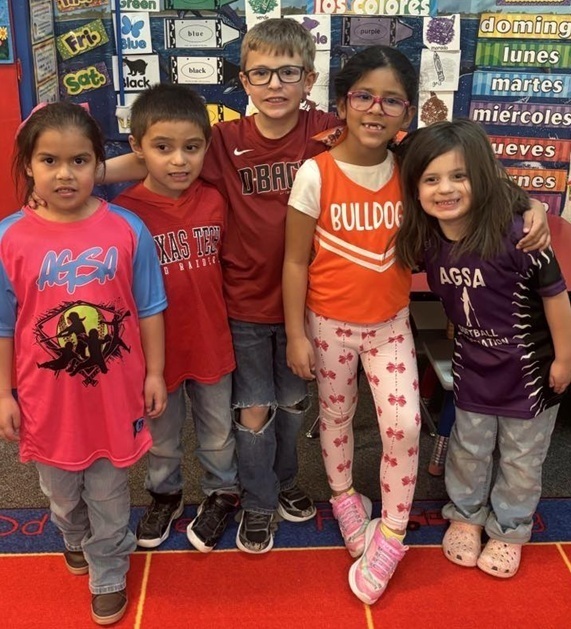 Five children pose for a photo. They wear team attire.