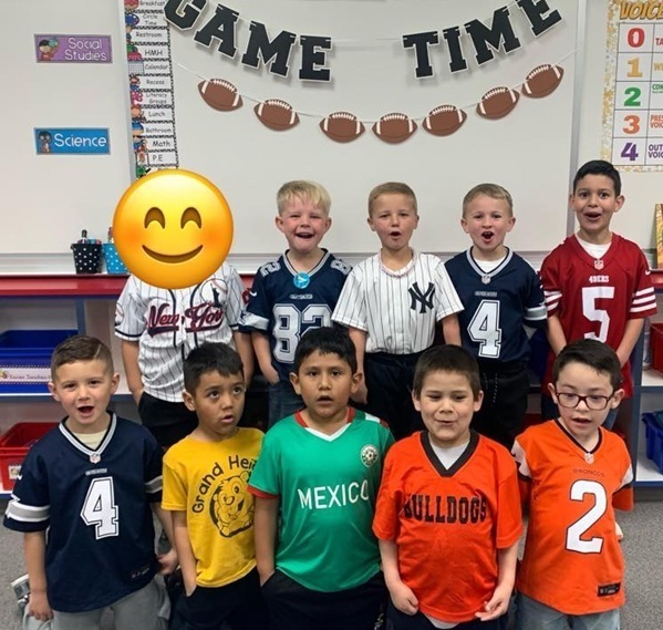 A group of boys wearing jerseys pose for a photo. They appear to be yelling something.