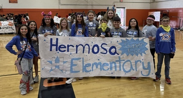 A group of children hold a banner reading "Hermosa Elementary Superkids."
