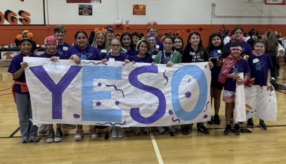 A group of children hold a banner reading "Yeso."