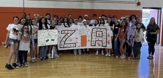 A group of preteens hold a banner reading "Zia."