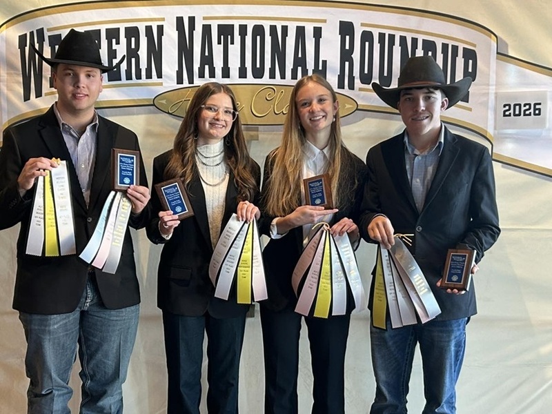Two teen boys and two teen girls in jackets and jeans pose for a photo. All are holding up a handful of ribbons and a small plaque. The boys are wearing black cowboy hats.