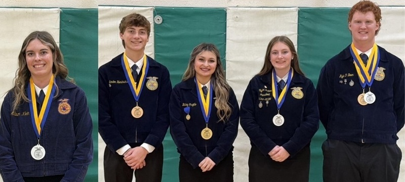 Three teen girls and two teen boys wearing blue FFA jackets and medals around their necks pose for a photo in front of green and white wall-mounted mats.