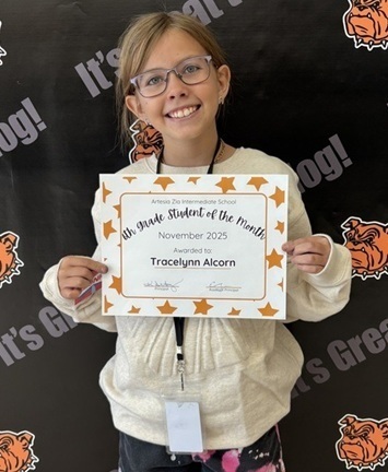 A teen girl in a white jacket holds a certificate that reads "Sixth-Grade Student of the Month".