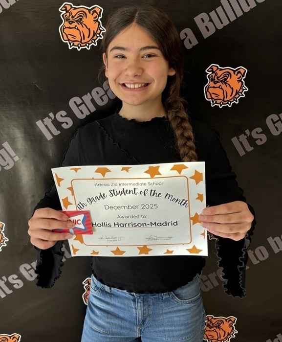 A preteen girl in a black top and jeans holds a certificate reading "Sixth-Grade Student of the Month".