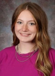 A teen girl in a pink top poses for a photo.
