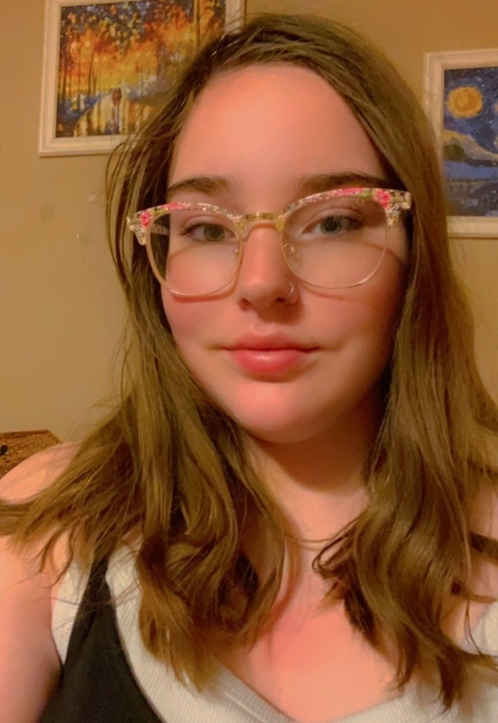 A teen girl in glasses poses for a photo.