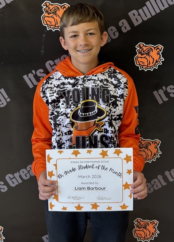 A teen boy in an orange, black and white sweatshirt holds a certificate reading "Seventh-Grade Student of the Month".