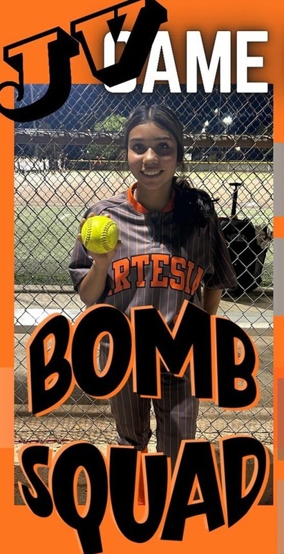 A teen girl in a grey and orange softball uniform poses for a photo holding a softball.