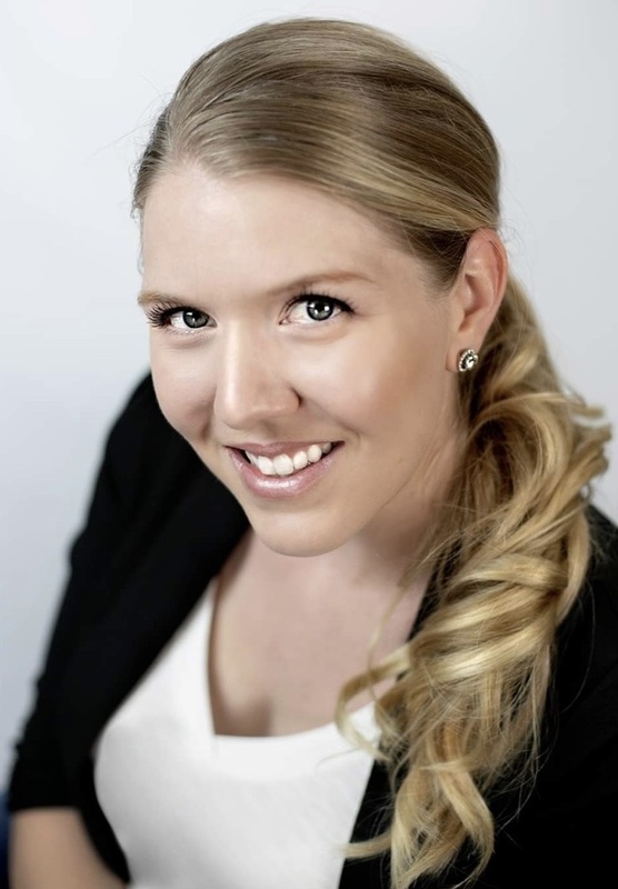 A female teacher with blonde hair looks upward at the camera.