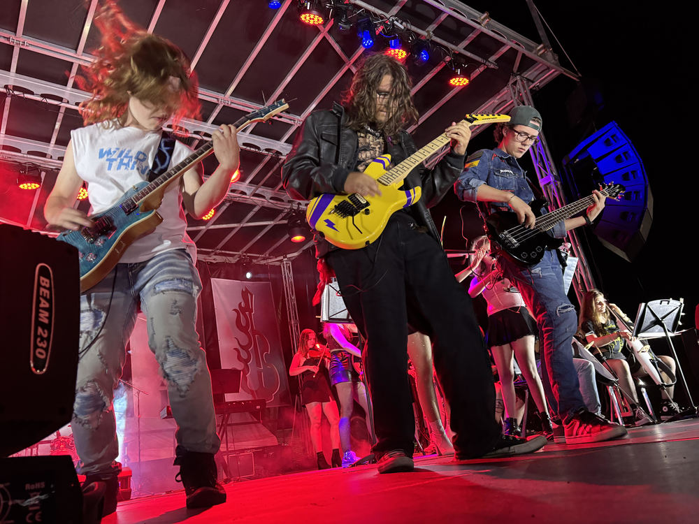 three guitar players on stage for Mayhem Concert