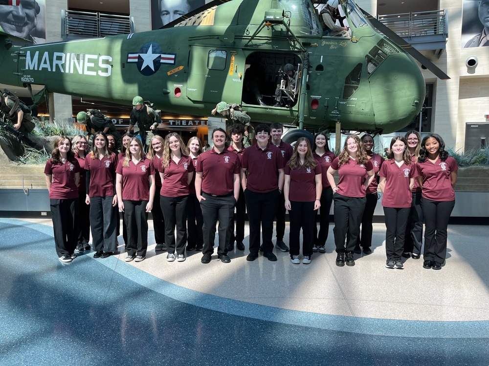 Choir members standing in front of marine helicopter in musium