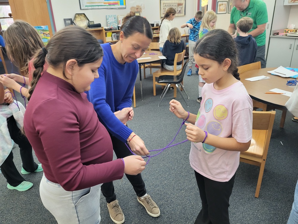 girls working with math professor to solve a topology puzzle