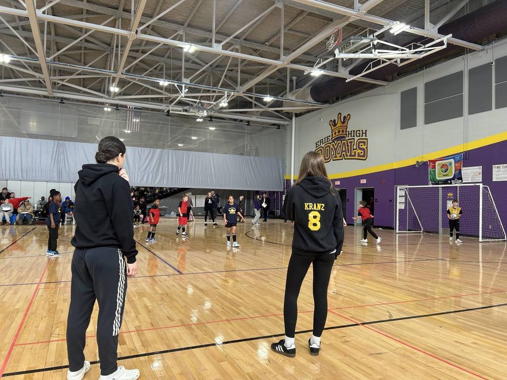 Students playing soccer in a gym.