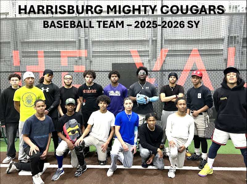 Group photo of the Harrisburg Mighty Cougars baseball team for the 2025–2026 school year. About fifteen teenage players pose together inside an indoor training facility with turf flooring and netting behind them. Some players stand in the back row while others kneel in front, wearing a mix of baseball gear and athletic clothing such as hoodies, T-shirts, gloves, and caps. A large banner above them reads “Harrisburg Mighty Cougars – Baseball Team – 2025–2026 SY.”