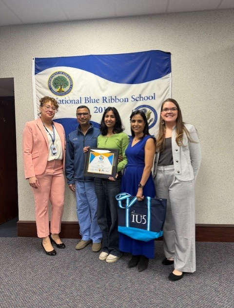 Young girl holding her award is standing next to her parents and staff from Collegiate Academy.