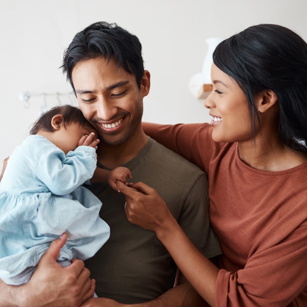 Young Latino parents hold newborn baby girl