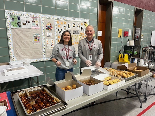 2 Staff Members standing behind table of goodies.