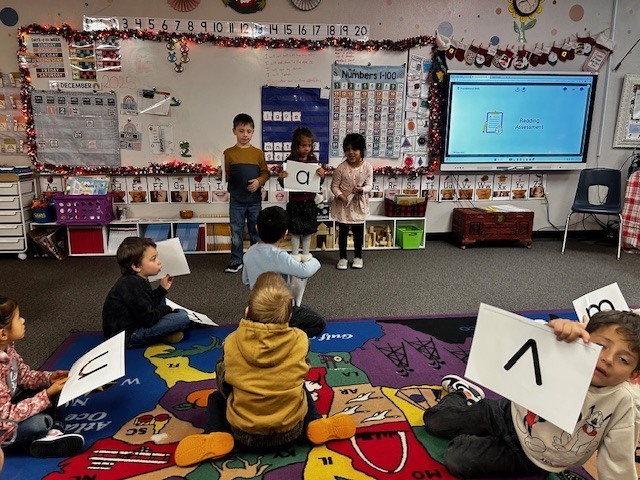 Kindergarteners sitting on the carpet learning about letters