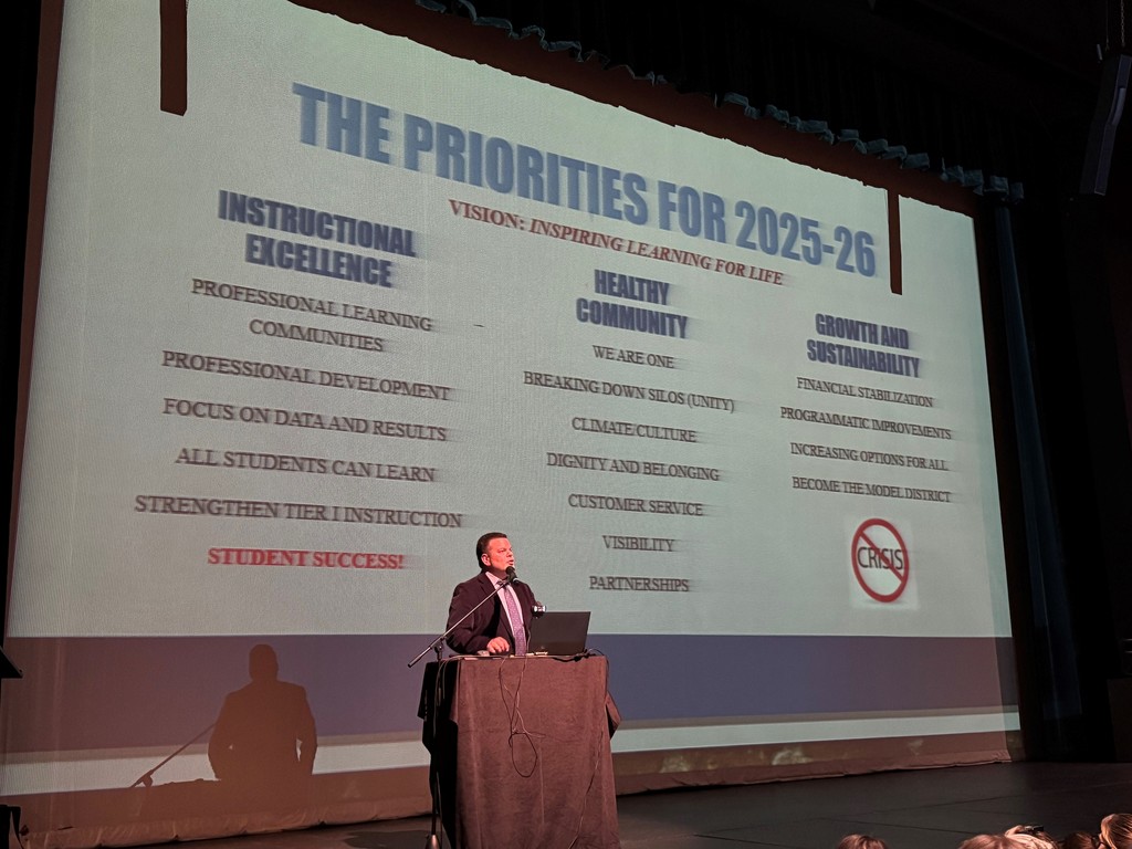 Superintendent Hattrick standing on stage delivering welcoming the staff back for the 2025-26 school year