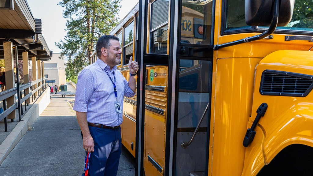 Superintendent Hattrick gives a thumbs up to students arriving on the school bus