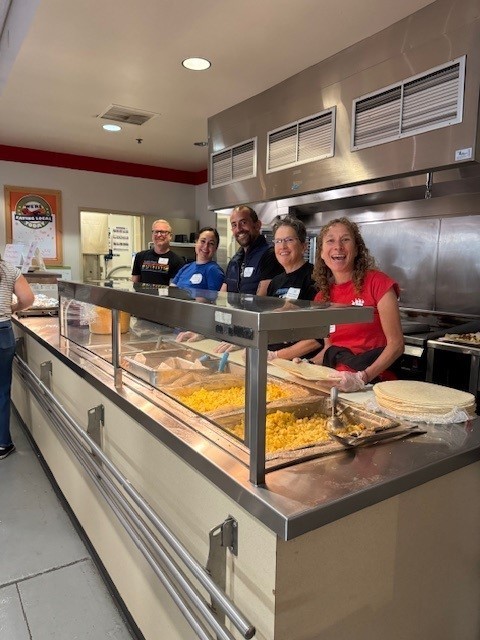 School Board Members behind the kitchen counter preparing to serve breakfast at the 2025-26 Welcome Back Event for ASD Staff