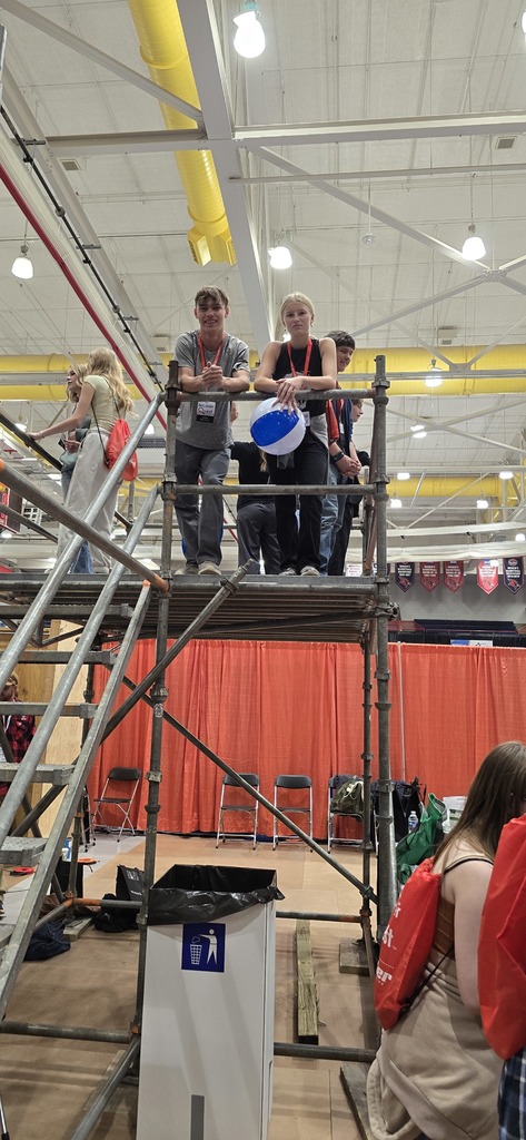 Students standing on scaffolding. 