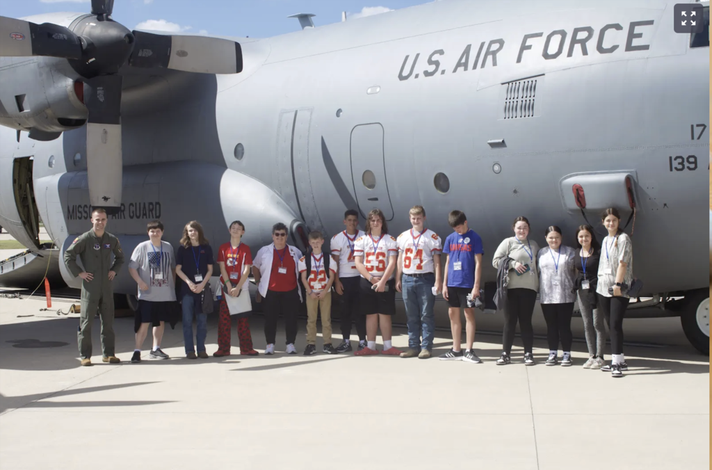Students standing in front of a large airforce plane