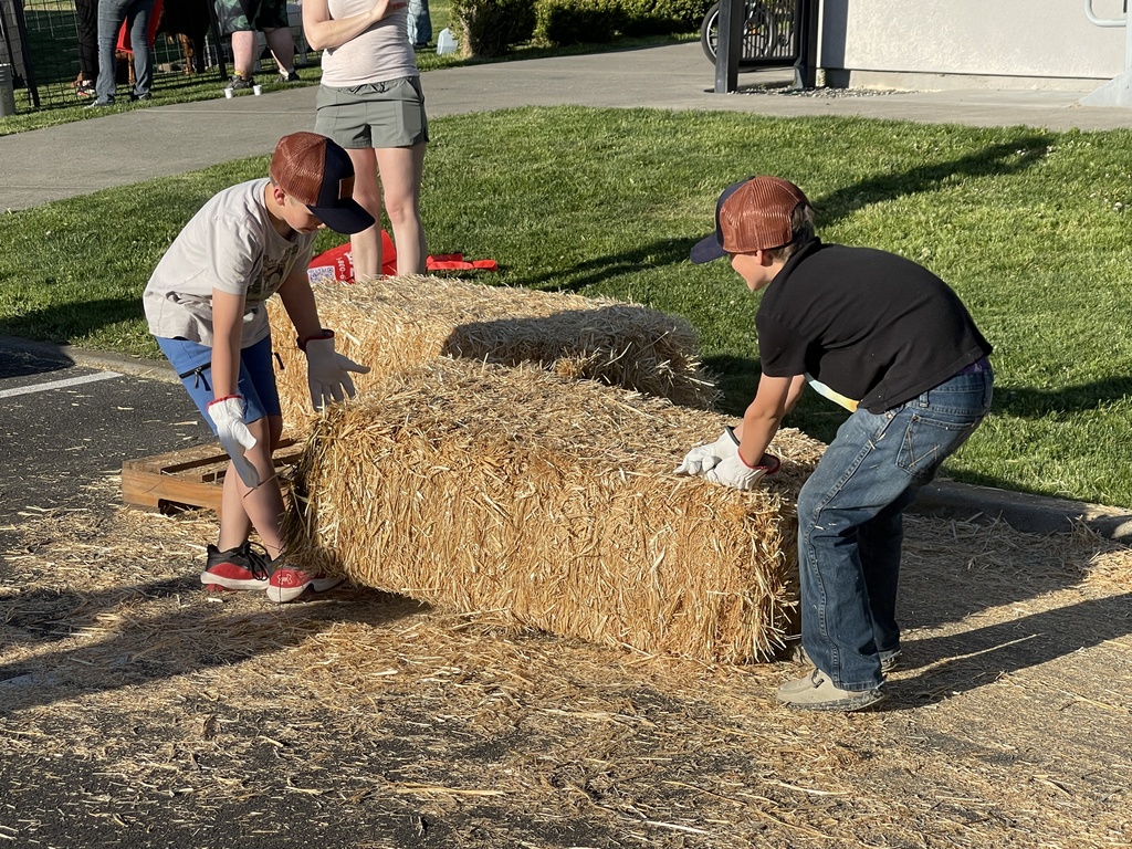 two young boys lifting a hay bale