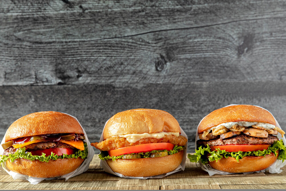 A closeup photo of three hamburgers. One appears to have chicken, the other beef and the third unknown, perhaps just veggies.