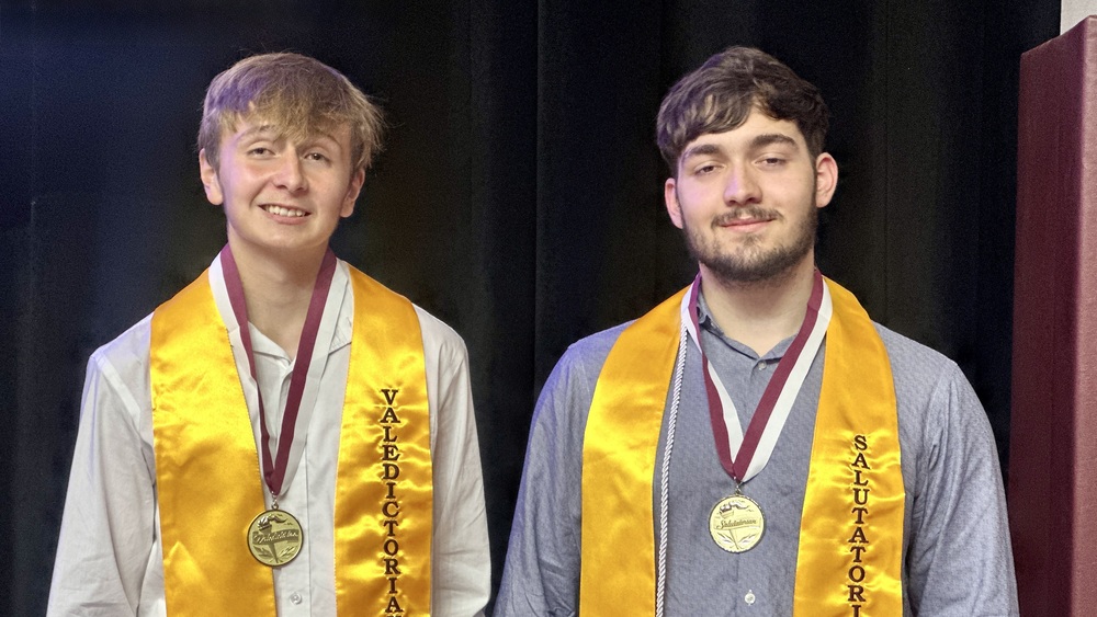 Athens High School valedictorian Gaden Riquelme (left) and salutatorian Gage Stasko stand side by side wearing gold graduation stoles and medals recognizing their academic honors.