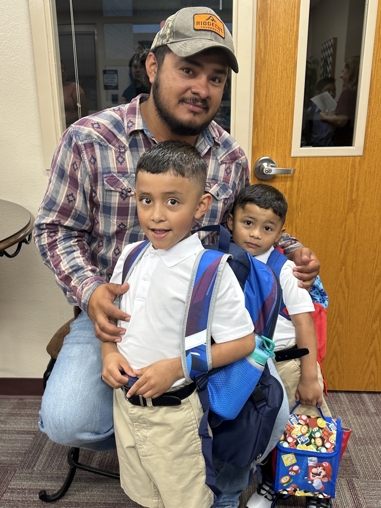 Two young boys with a man presumably their father huddle together in an office