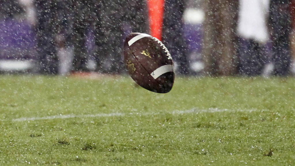 Photo of a fooball bouncing on a rainy field