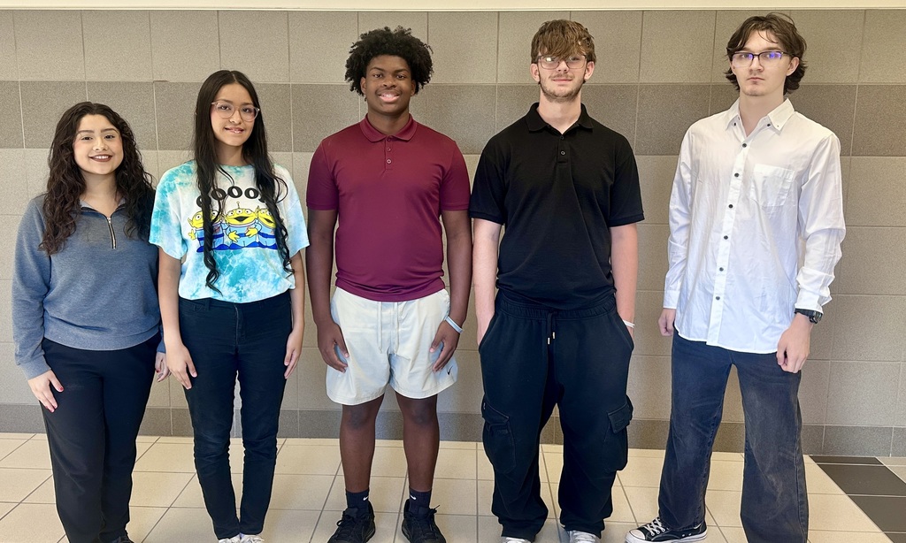 Five Athens High School students stand side by side in a school hallway, smiling for the camera. From left to right are Victoria Juarez, Azaneth Flores, Kaison Walker, Dominik Snow, and Kane Mitchell, who earned places in the TMEA Region 21 Honor Choir. They are dressed in casual and semi-formal attire against a tiled wall background.