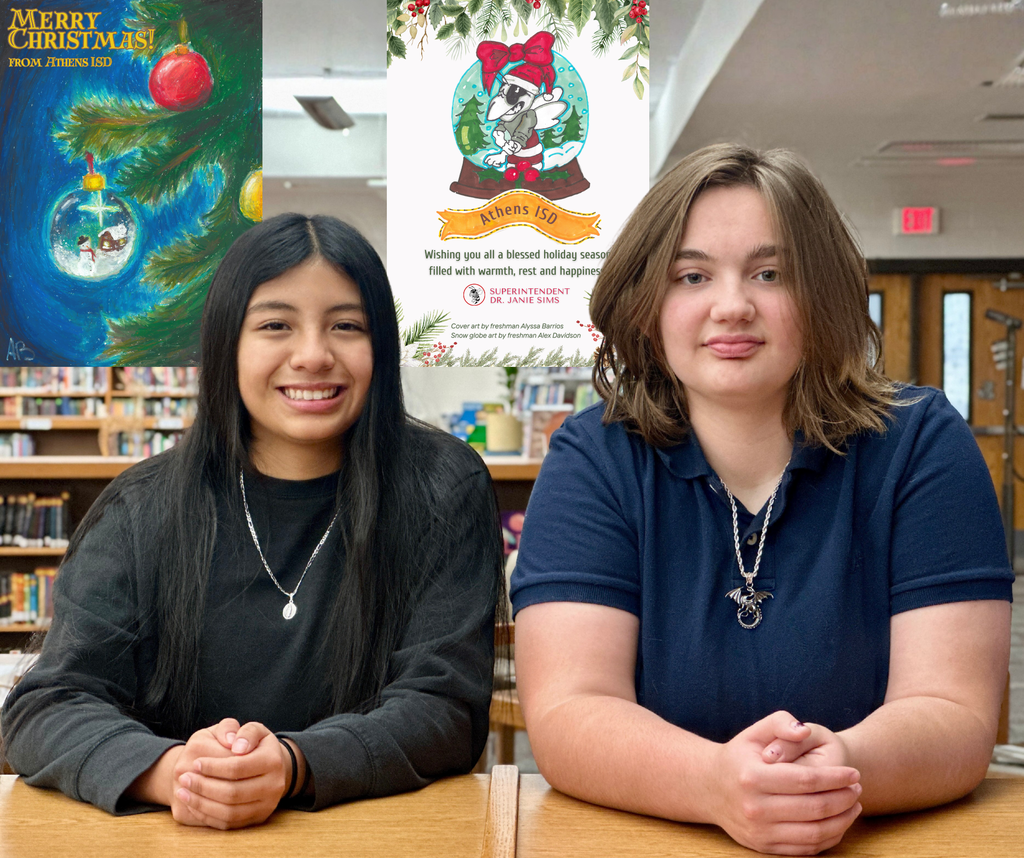 Two student artists lean forward with their arms resting on a low bookshelf in a school library, smiling at the camera. Behind their heads, the front and back of the same Athens ISD Christmas postcard design have been digitally inserted. The front shows a hand-painted Christmas tree branch with ornaments, including a red ornament and a clear glass ornament with a small winter scene inside, with the text “Merry Christmas from Athens ISD.” The back features a matching holiday design with the Athens ISD hornet mascot inside a snow globe, decorated with greenery and a bow, along with a printed holiday message and credits acknowledging the student artists and superintendent.