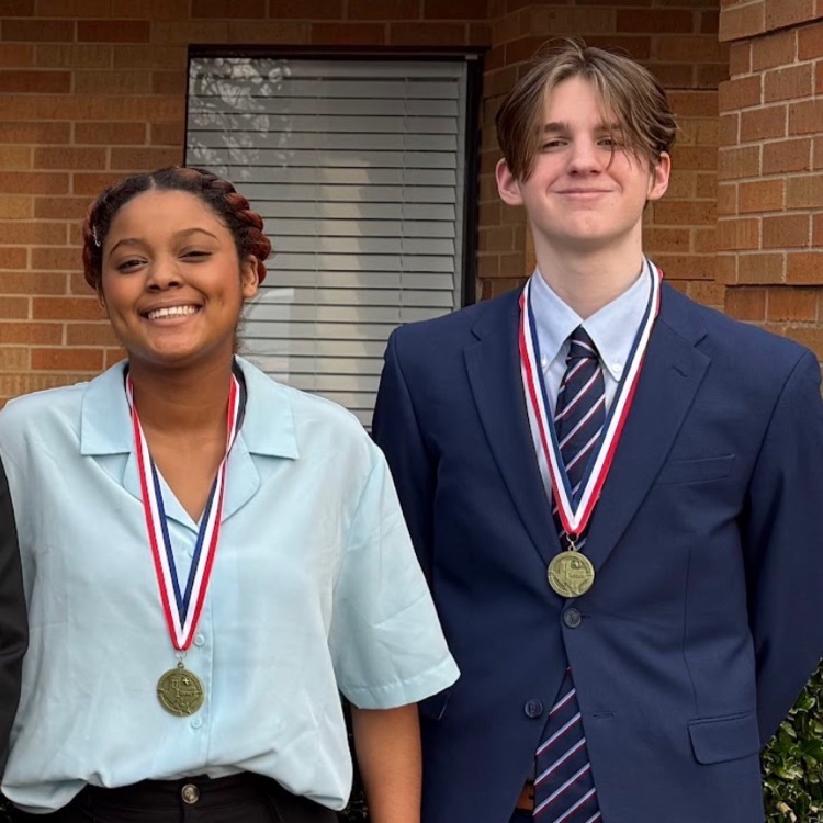 Photo of a young woman and a young man both dressed nicely and wearing medals around their necks