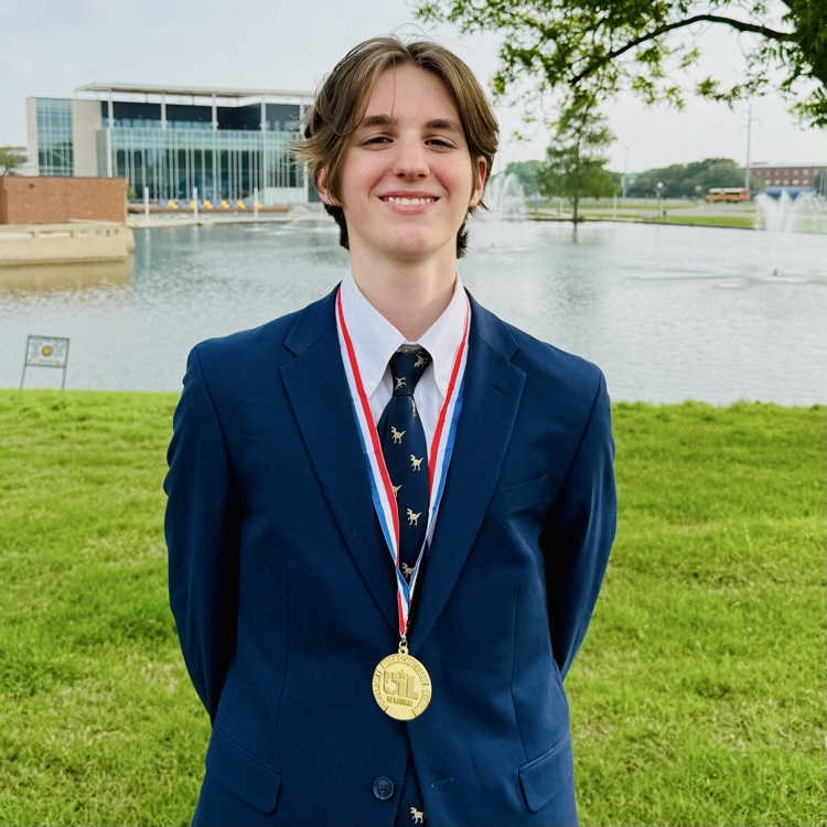photo of Liam in a suit with a gold medal around his neck and a lace in the background 