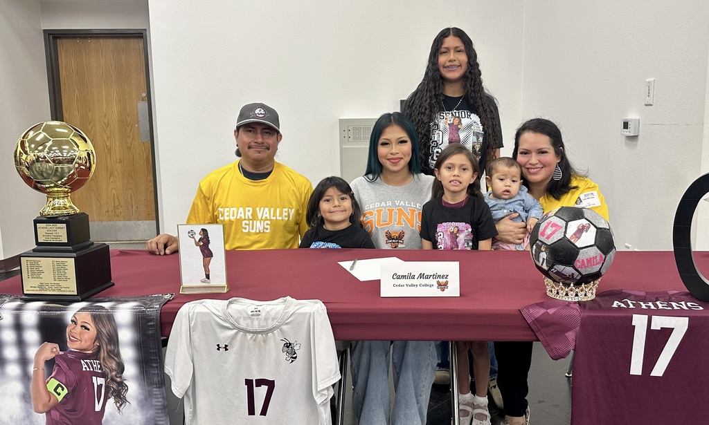 Teen girl seated behind table surrounded by family members.
